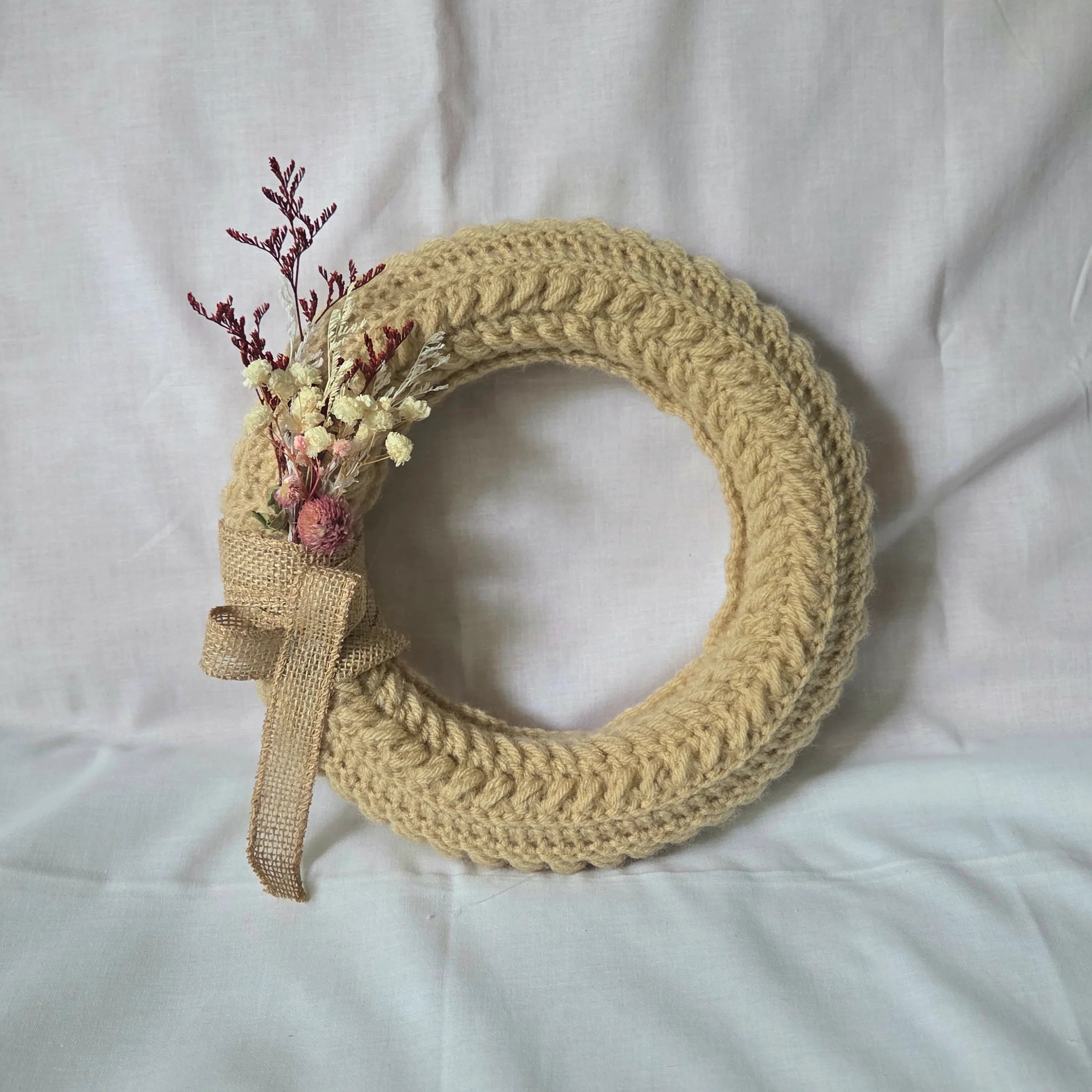 Handmade crochet wreath with dried flowers and burlap ribbon, cozy home decor