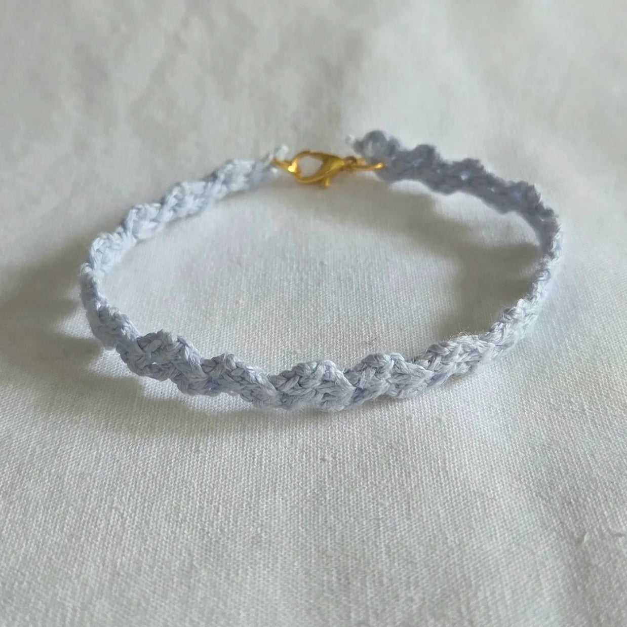 Handmade crochet bracelet in soft blue with gold clasp, cozy and creative accessory for everyday wear