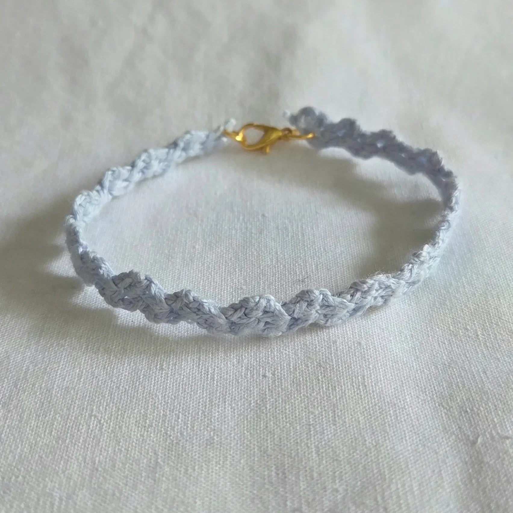 Handmade crochet bracelet in soft blue with gold clasp, cozy and creative accessory for everyday wear