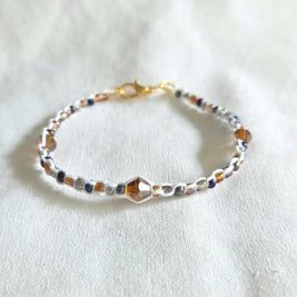 Handmade beaded bracelet with colorful crystals and gold clasp on white fabric