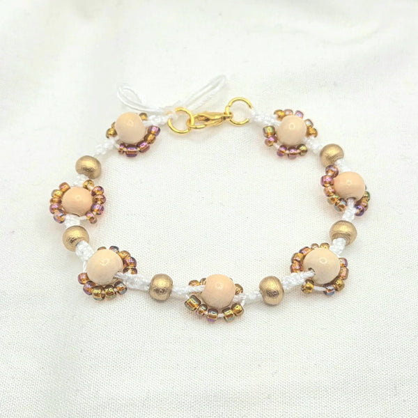 Handmade beaded bracelet with cream wood beads, gold accents, and iridescent seed beads on white cord