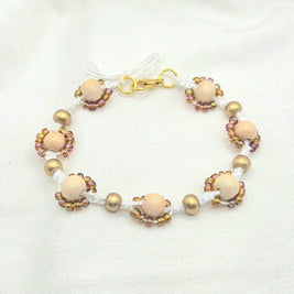 Handmade beaded bracelet with cream wood beads, gold accents, and iridescent seed beads on white cord