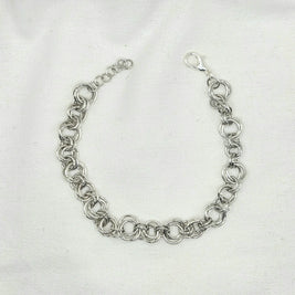 Silver chainmaille bracelet with interlocking rings and lobster clasp on white fabric