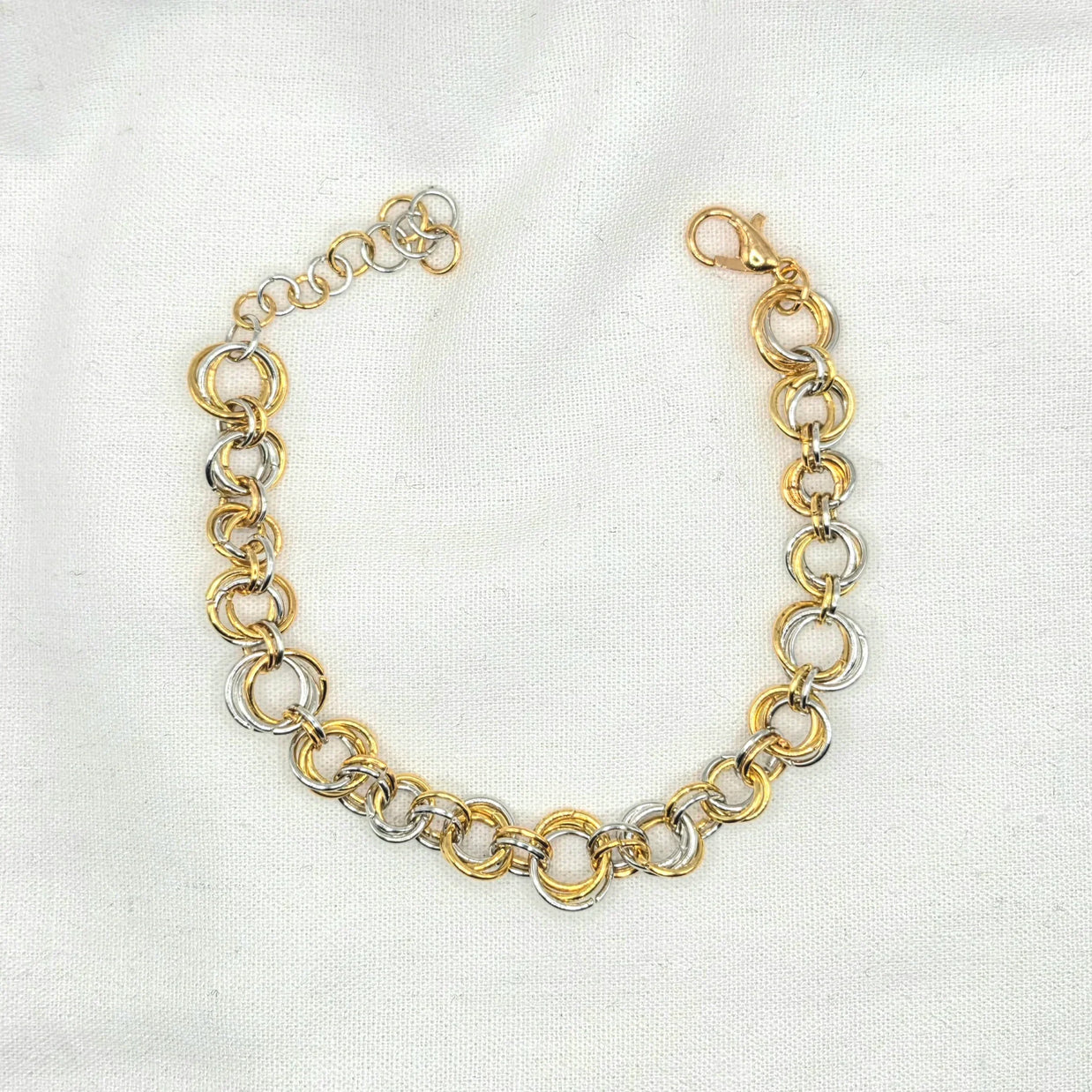 Gold and silver interlocking chain necklace on white fabric, elegant handmade jewelry piece