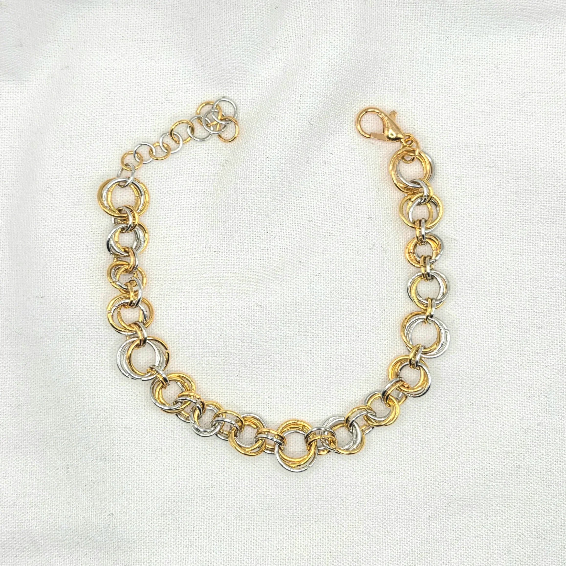 Gold and silver interlocking chain necklace on white fabric, elegant handmade jewelry piece