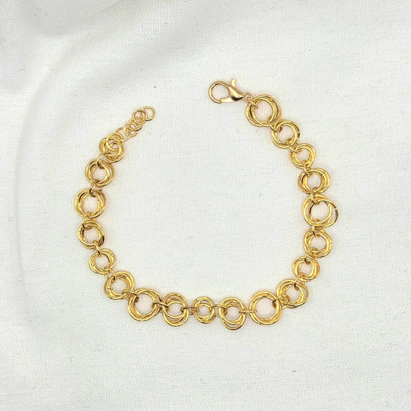 Gold tone interlocking circle chain bracelet with lobster clasp on white fabric background