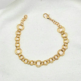 Gold-toned double link chain bracelet with lobster clasp on white fabric background