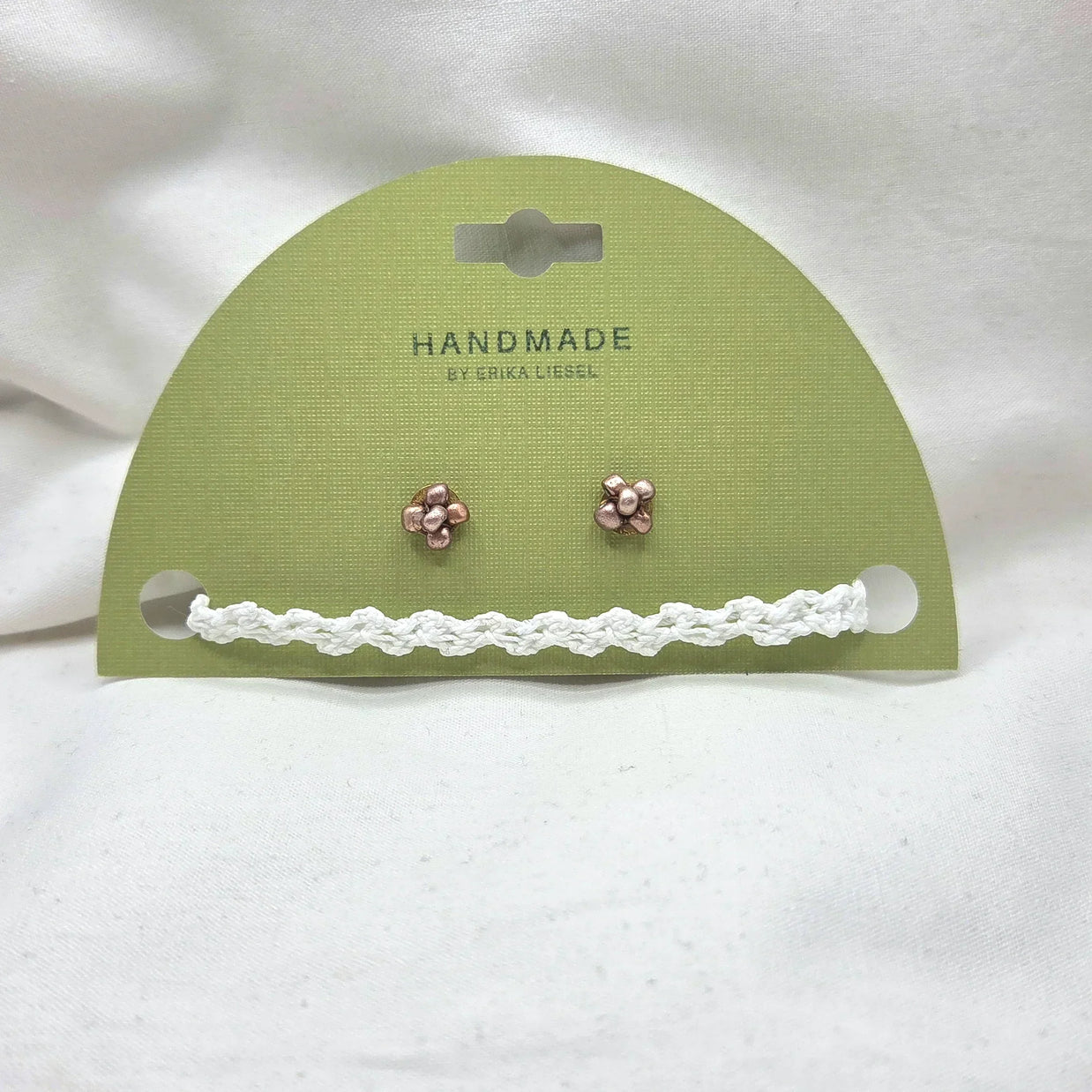 Handmade copper flower stud earrings with white crochet trim on green card