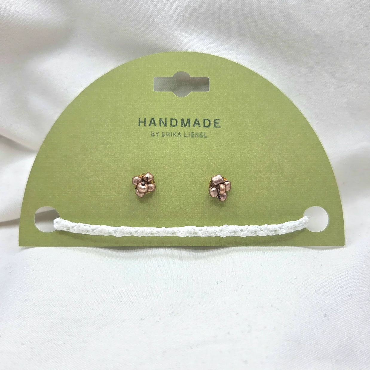 Handmade copper jingle bell earrings on green card with white crochet trim, cozy holiday gift