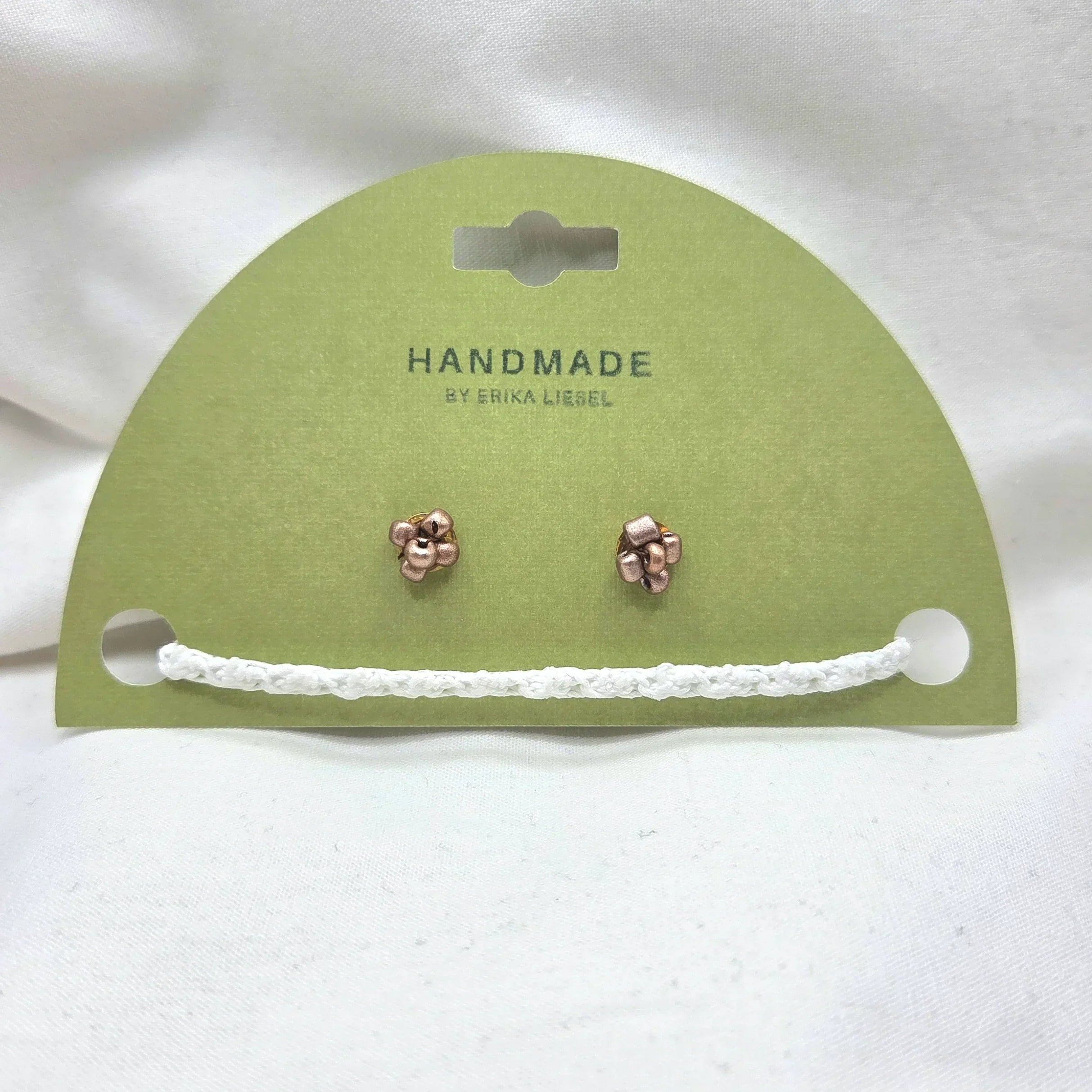 Handmade copper jingle bell earrings on green card with white crochet trim, cozy holiday gift