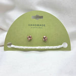 Handmade copper flower stud earrings with white crochet accent on green card