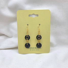 Handmade black button earrings with gold chains on yellow card, cozy crochet gift idea