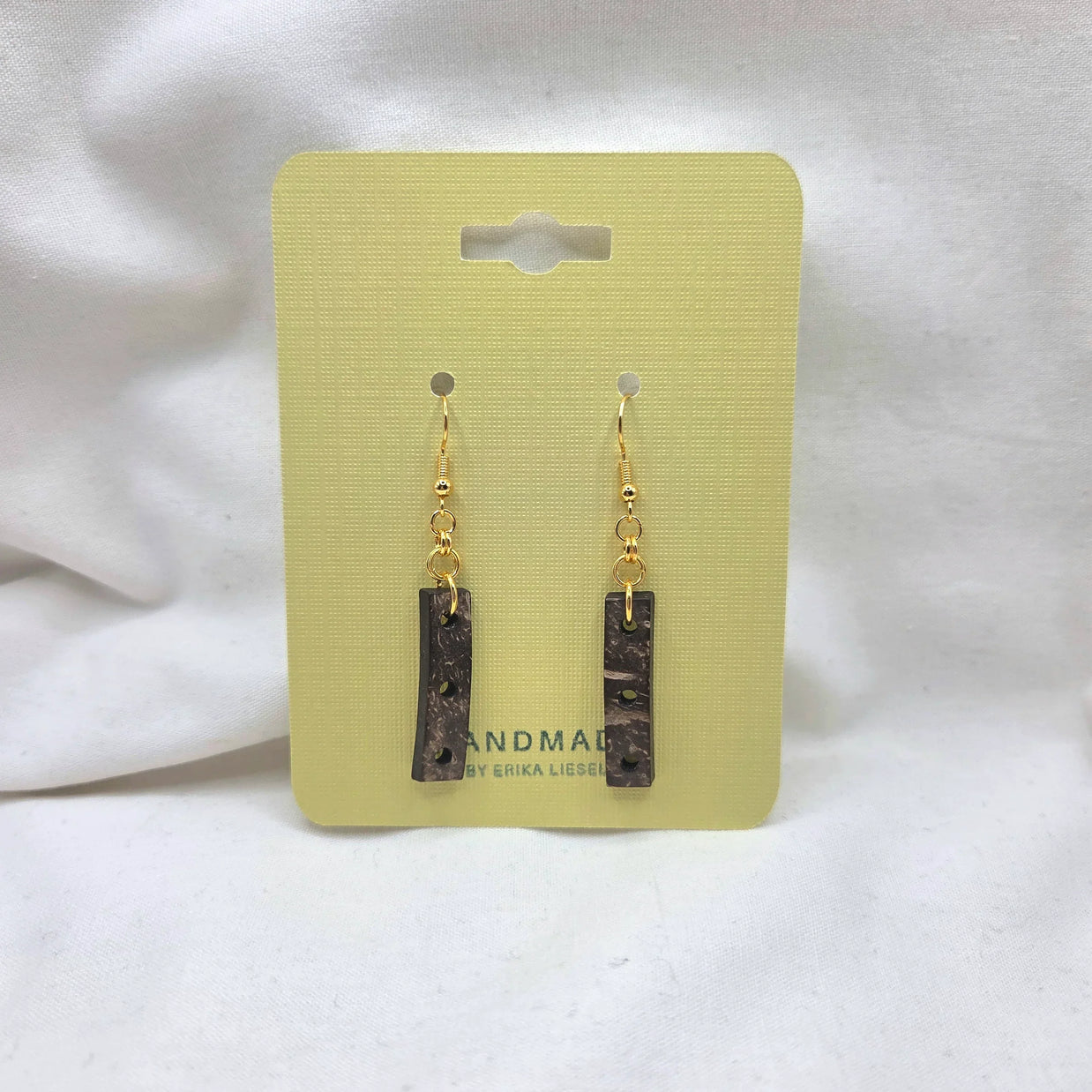 Handmade coconut shell drop earrings with gold hooks on yellow card, artisan jewelry gift