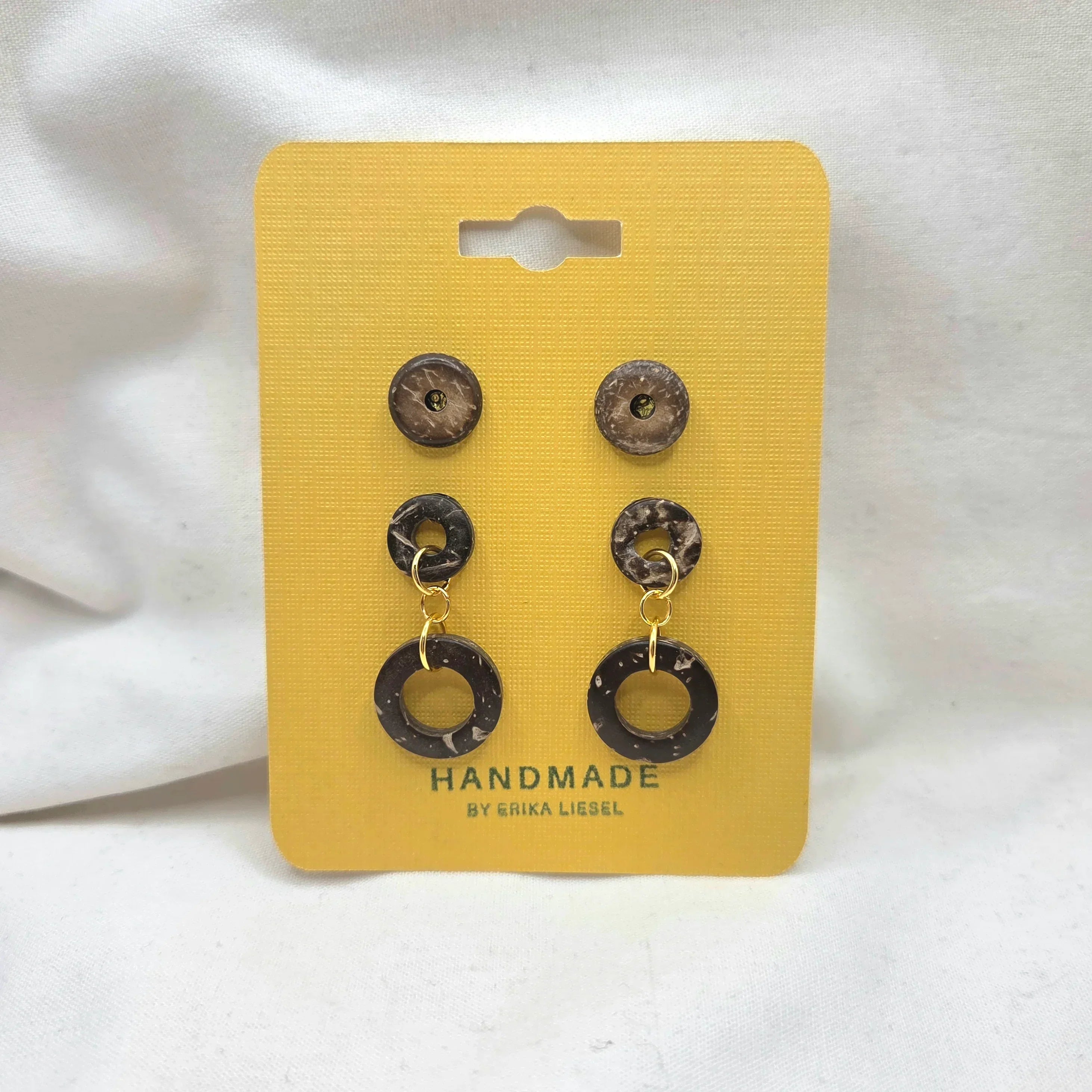 Handmade coconut shell dangle earrings with gold accents on yellow display card