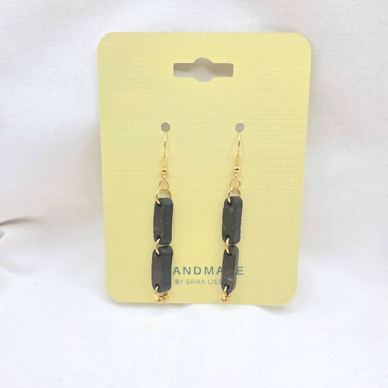 Handmade black rectangular drop earrings with gold chain links on yellow display card