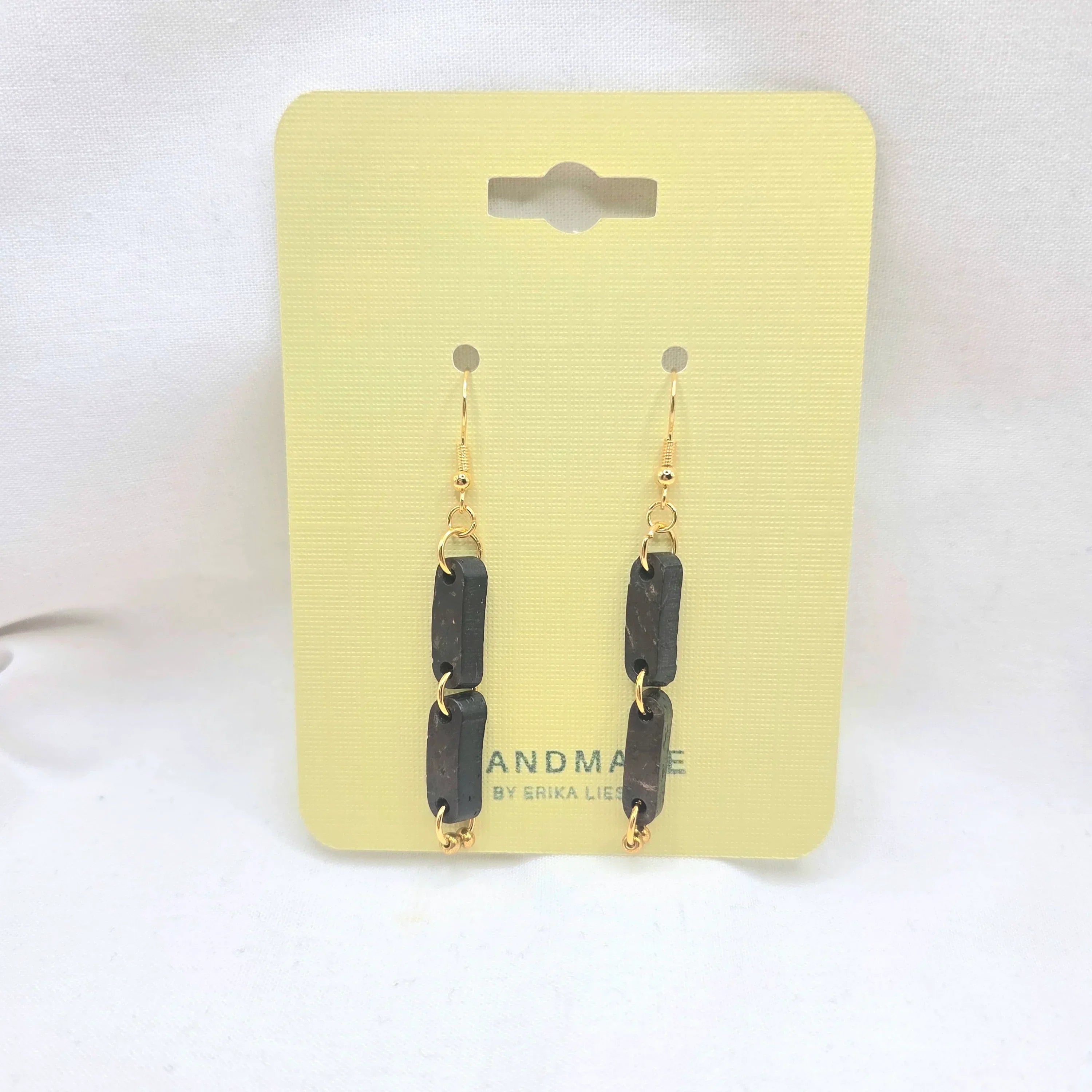 Handmade black rectangular drop earrings with gold chain links on yellow display card