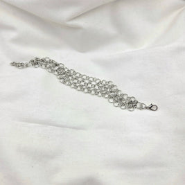 Silver chainmaille bracelet with lobster clasp on white fabric background