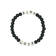 A beaded stretch bracelet on a plain white background, featuring black round beads and white letter beads spelling out 'HATE' on one side and 'LOVE' on the other.