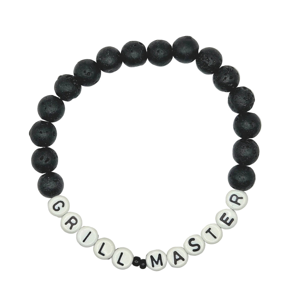 A beaded stretch bracelet on a white background, featuring black porous lava beads and white letter beads spelling out 'GRILL MASTER'.