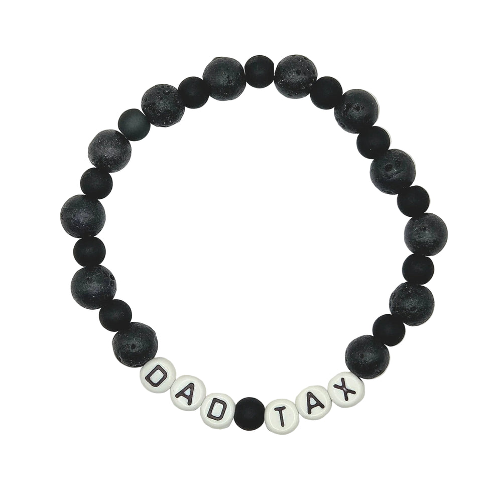 A beaded stretch bracelet on a white background, featuring matte black lava stone beads and white letter beads spelling 'DAD TAX'.