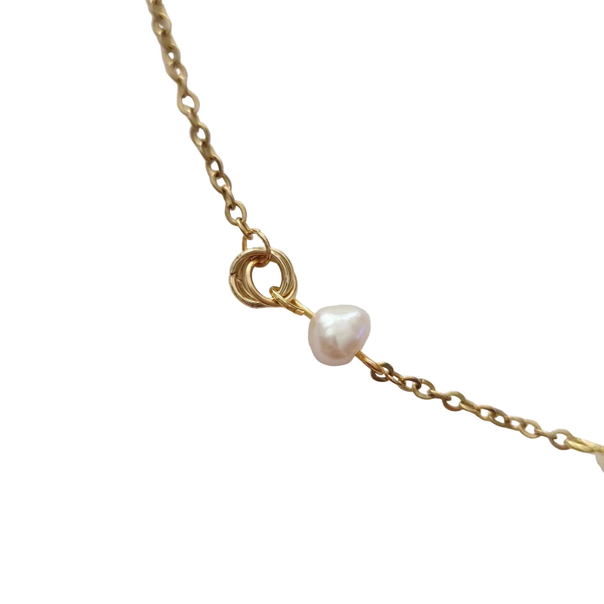 A close-up of a delicate gold chain necklace featuring a small, irregular white freshwater pearl and a triple-ring gold clasp, set against a plain light gray background.