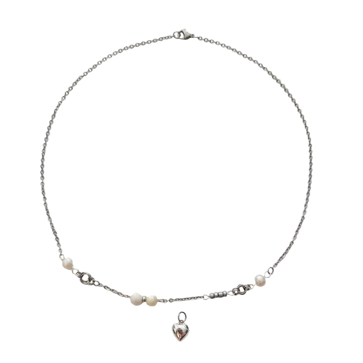 A delicate silver chain necklace featuring small white pearl beads and a dangling silver heart charm, displayed on a clean white background.