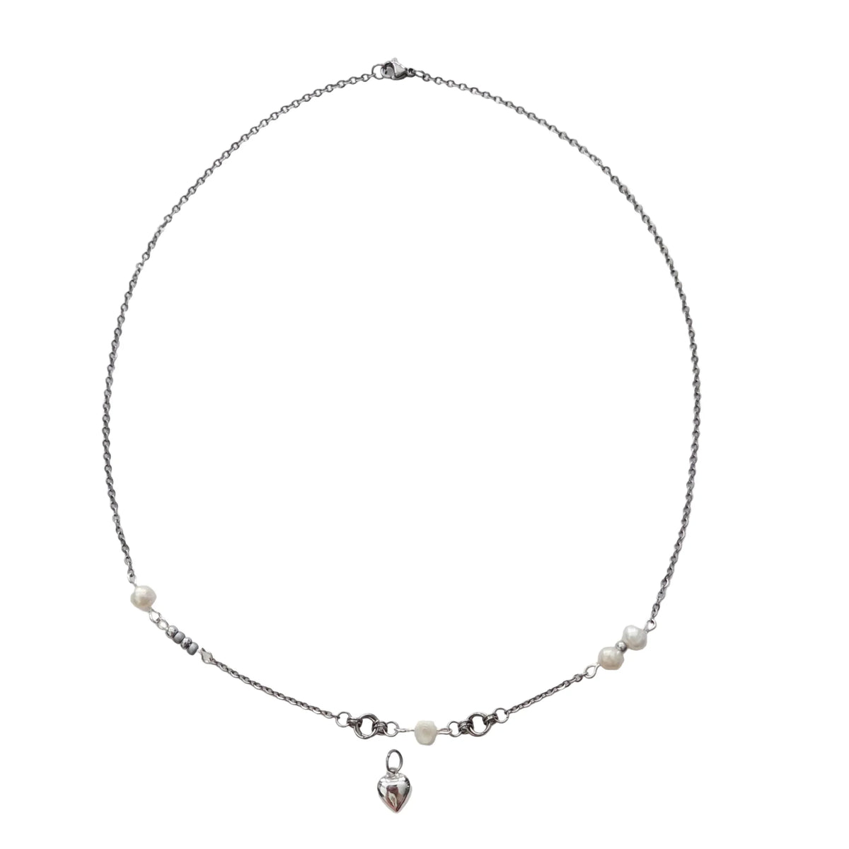 A delicate silver chain necklace featuring small white pearl beads and a small dangling heart charm, displayed on a plain white surface.