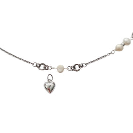 A silver chain necklace featuring a small polished heart charm, a white pearl bead, and a row of larger white pearls along the side, displayed on a light gray background.
