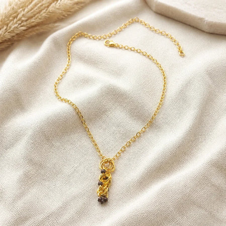 Delicate gold chain necklace with intricate pendant, styled on soft fabric for cozy, handmade charm.