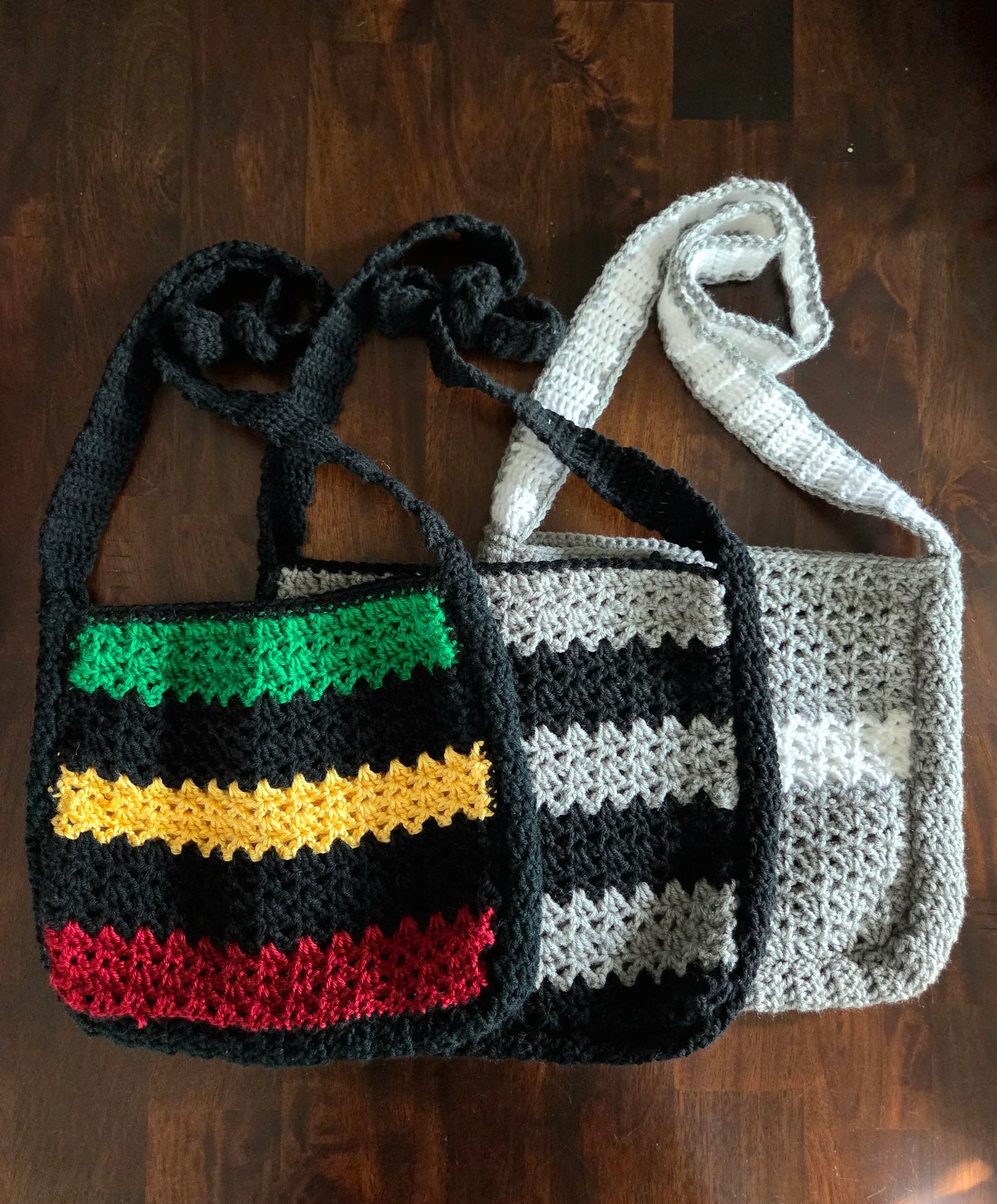 Handmade crochet bags with colorful stripes on a dark wooden table