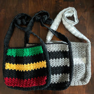 Handmade crochet bags with colorful stripes on a dark wooden table