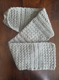 Gray crochet scarf with textured stitch detail on dark wood table