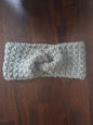 Gray chunky crochet headband with twist design on dark wooden table