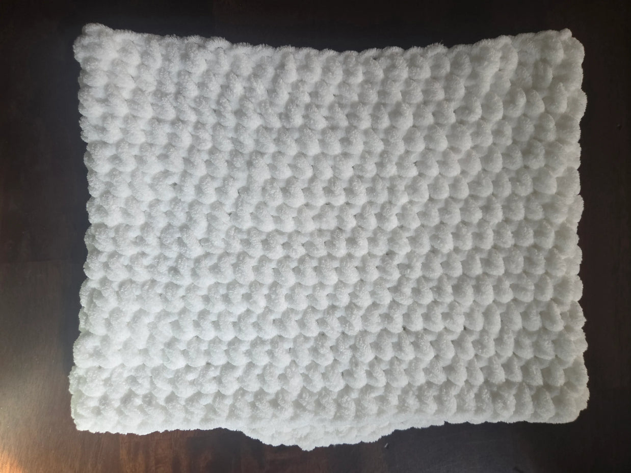 White textured bath mat with soft, fluffy bubble pattern on dark wooden floor