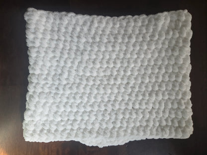 White textured bath mat with soft, fluffy bubble pattern on dark wooden floor