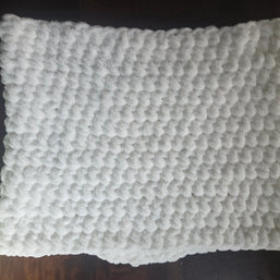 White textured bath mat with soft, fluffy bubble pattern on dark wooden floor