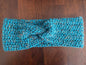 Handmade blue crochet headband with twist knot on wooden table