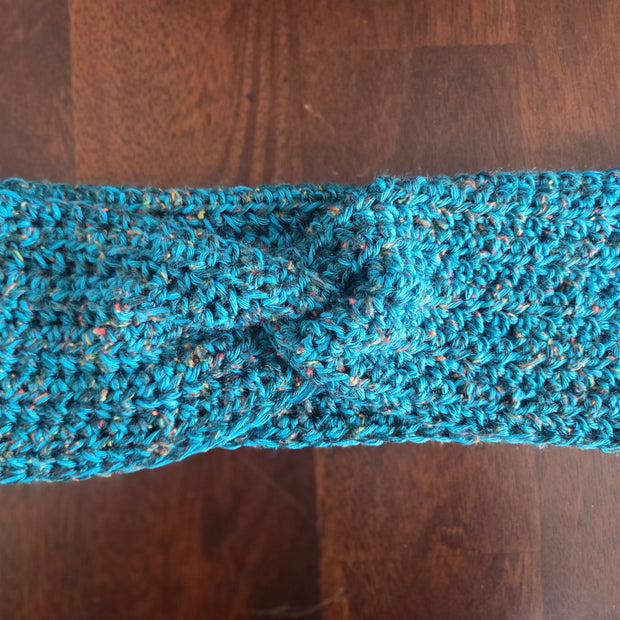 Handmade blue crochet headband with twist knot on wooden table