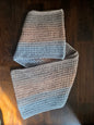 Handmade crochet scarf with grey and blue yarn on a dark wooden table
