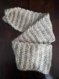Handmade chunky beige knit scarf on dark wood table