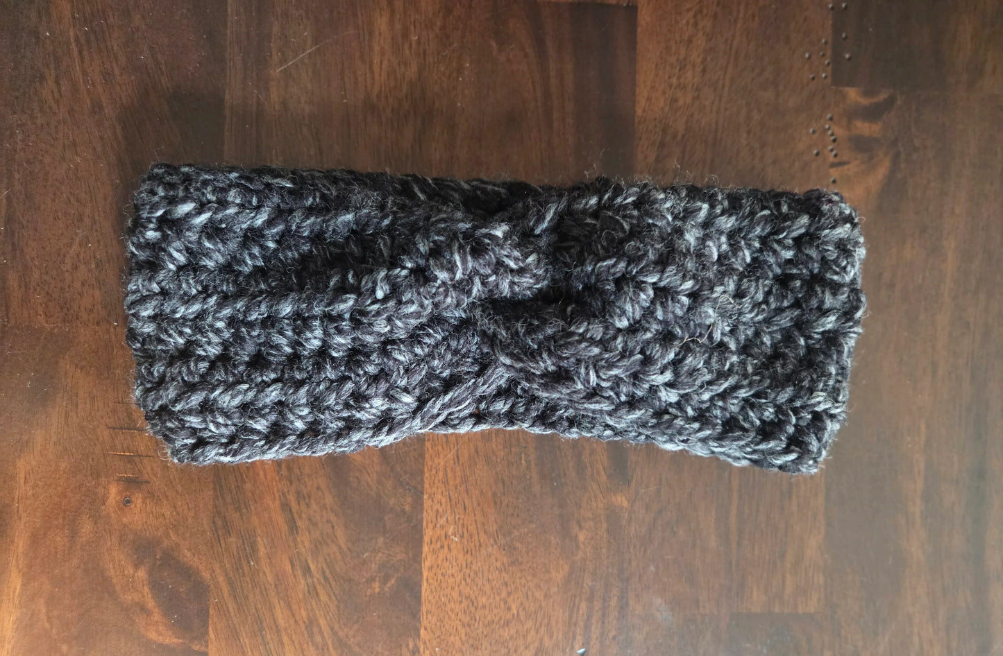 Handmade chunky knit charcoal headband on dark wooden table