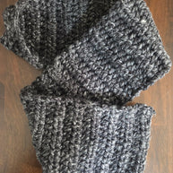 Handmade chunky dark gray crochet scarf on wooden surface