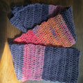 Handmade knitted scarf with navy and multicolor yarn on wooden surface