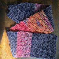 Handmade knitted scarf with navy and multicolor yarn on wooden surface