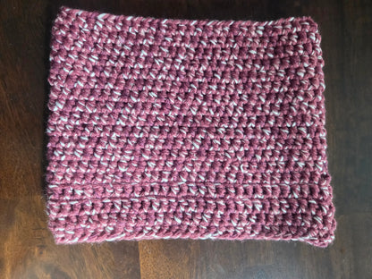 Handmade crochet cowl scarf in maroon and white yarn on wooden table