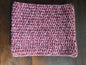 Handmade crochet cowl scarf in maroon and white yarn on wooden table