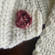 White crocheted fabric with red heart-shaped detail on dark wood surface