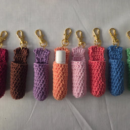 Colorful crochet lip balm holders with gold keychains on light background