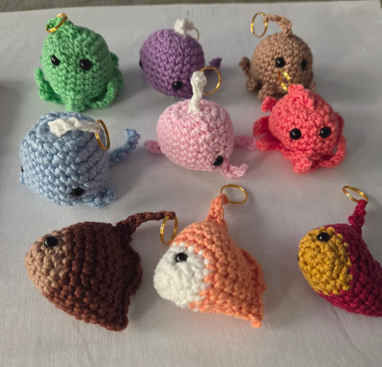 Colorful crochet sea creature keychains arranged on a white surface
