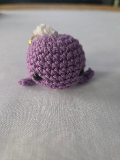 Purple crochet amigurumi plush keychain with black eyes on a white surface